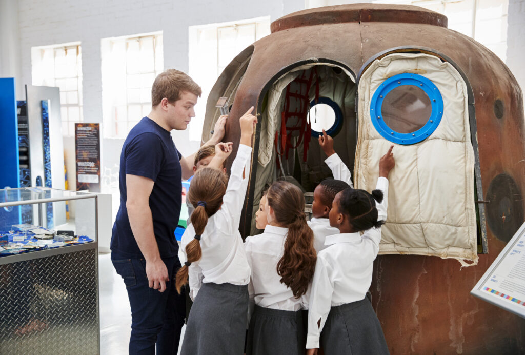 Kids and teacher look at a space capsule at a science centre