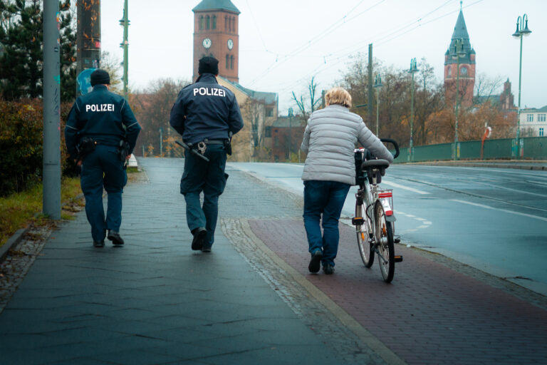 Police walking close to a female with a bicycle